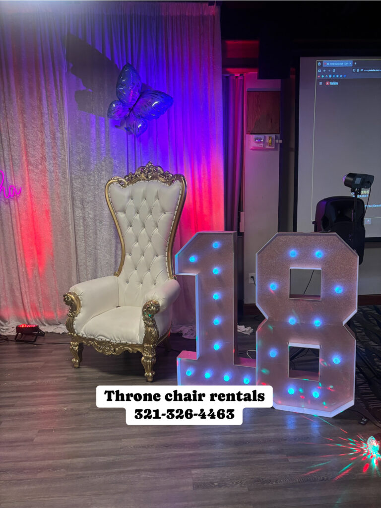 Gold and white throne chair beside illuminated number 18 at a birthday event